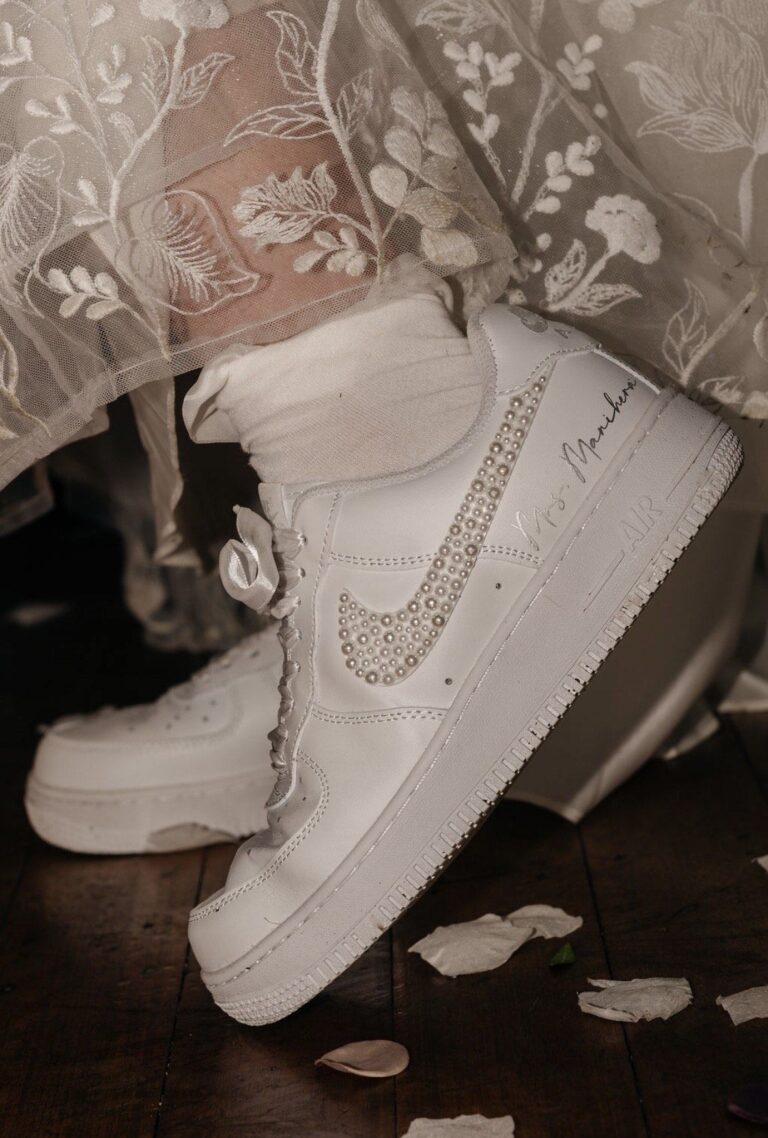 Bride's feet in custom sneakers beneath an embroidered wedding veil