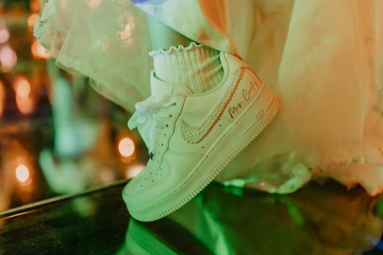 Pearl-encrusted custom sneakers peeking out under a bride's dress hem