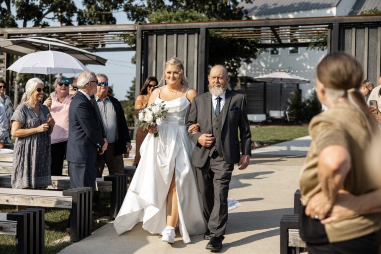 Bride walking down the aisle with her father, wearing custom sneakers