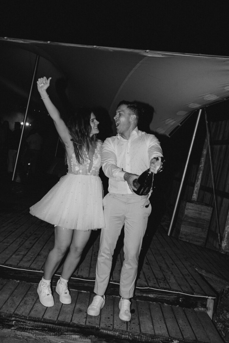 Bride and groom dancing with champagne, custom sneakers on the floor