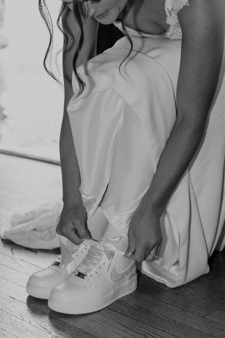 Bride lacing up her custom wedding sneakers before the ceremony