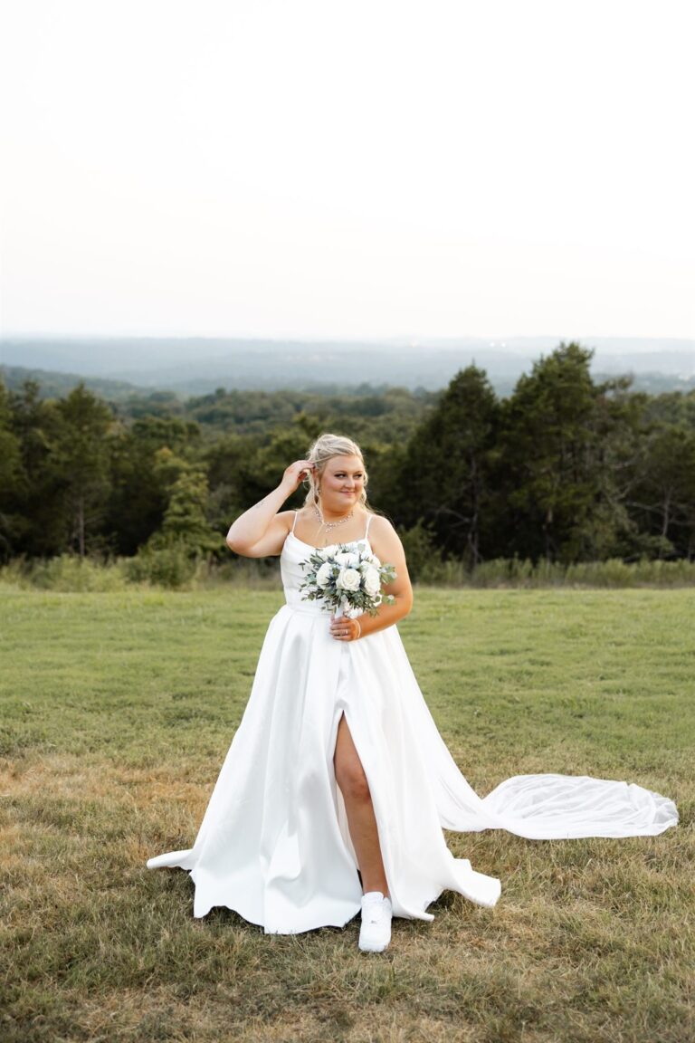Bride alone in a field with her bouquet, wearing custom sneakers