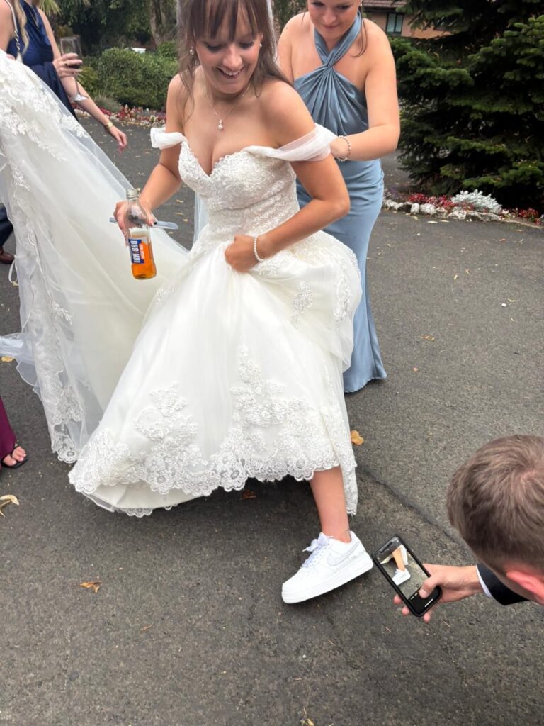Bride laughing with friends, looking at her custom wedding sneakers