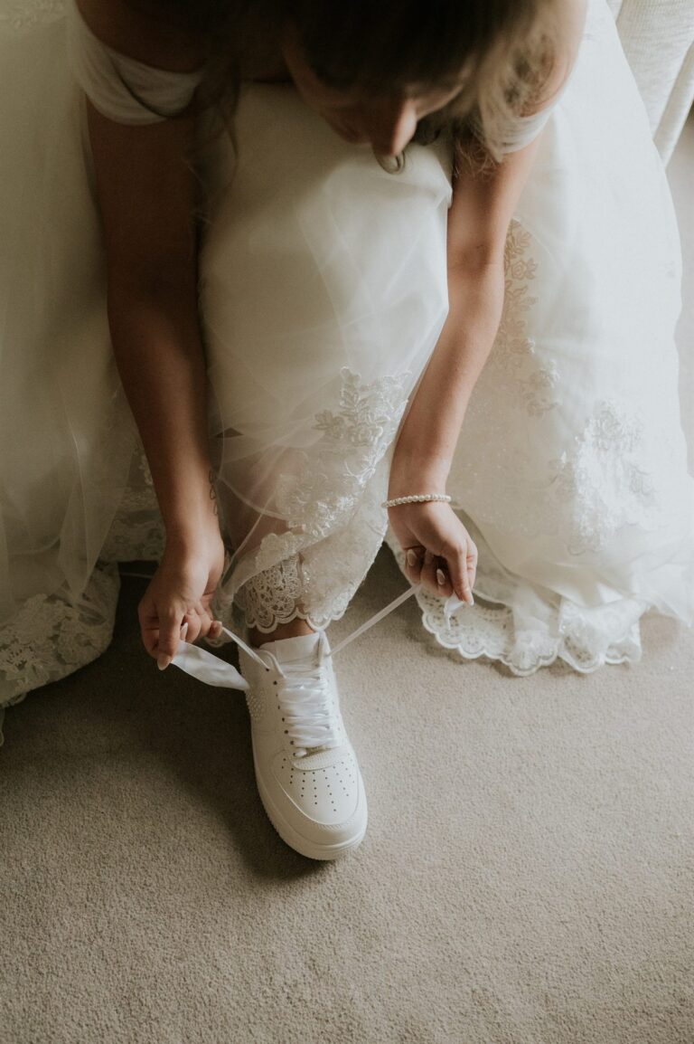 Bride bending down to tie the laces of her custom wedding sneakers
